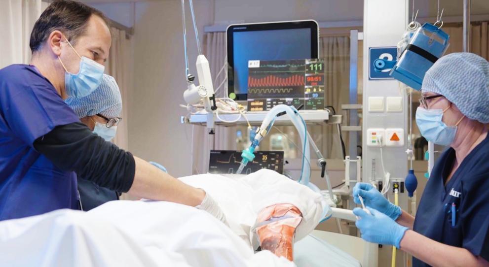 A burns team work on a mannequin in a hospital bed during a simulated burns exercise.