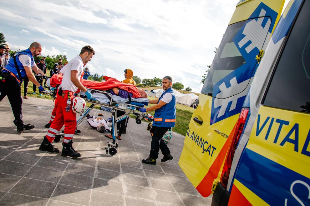 A patient on a stretcher is transported to an ambulance by a medical team.
