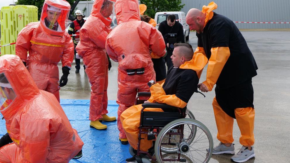 A person in a wheelchair is escorted to be a disinfection area during a CBRN exercise.