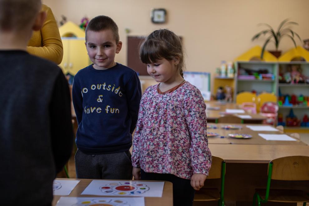 Two children standing around a table in a classroom.