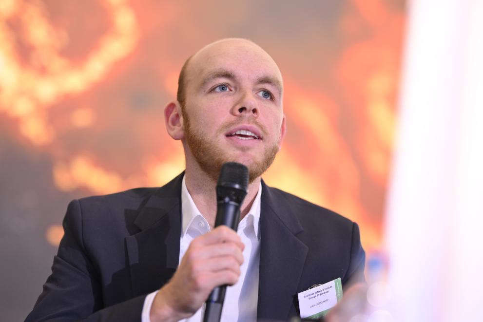 Lukas Liessenhof during his speech, seated, with a microphone in his hand. 