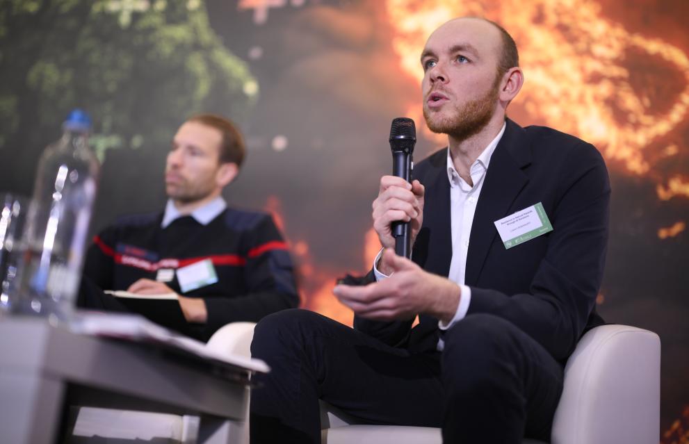 Lukas Liesenhoff during his speech, seated, facing the audience, gesturing with his hand.