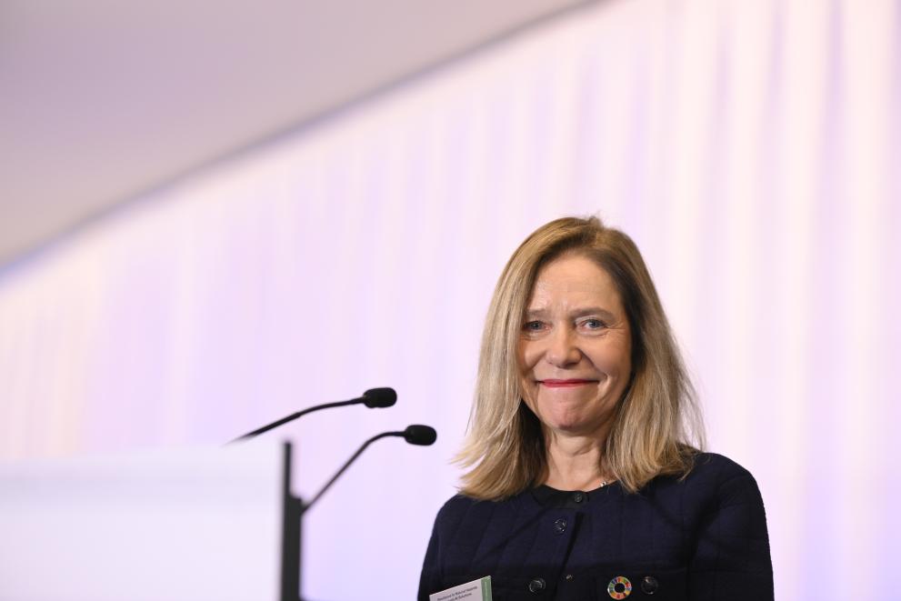 Celeste Saulo looks into the camera smiling, she is on stage in front of a microphone, while delivering her speech.