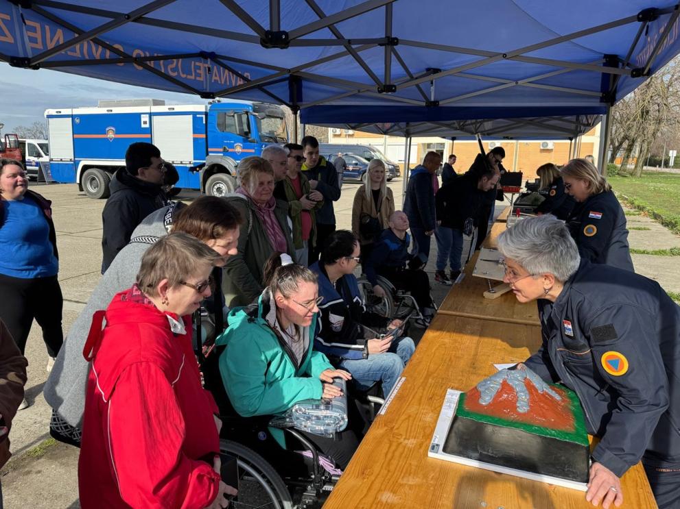 A wheelchair user engages directly with a first responder who explains the risk of volcano eruptions.
