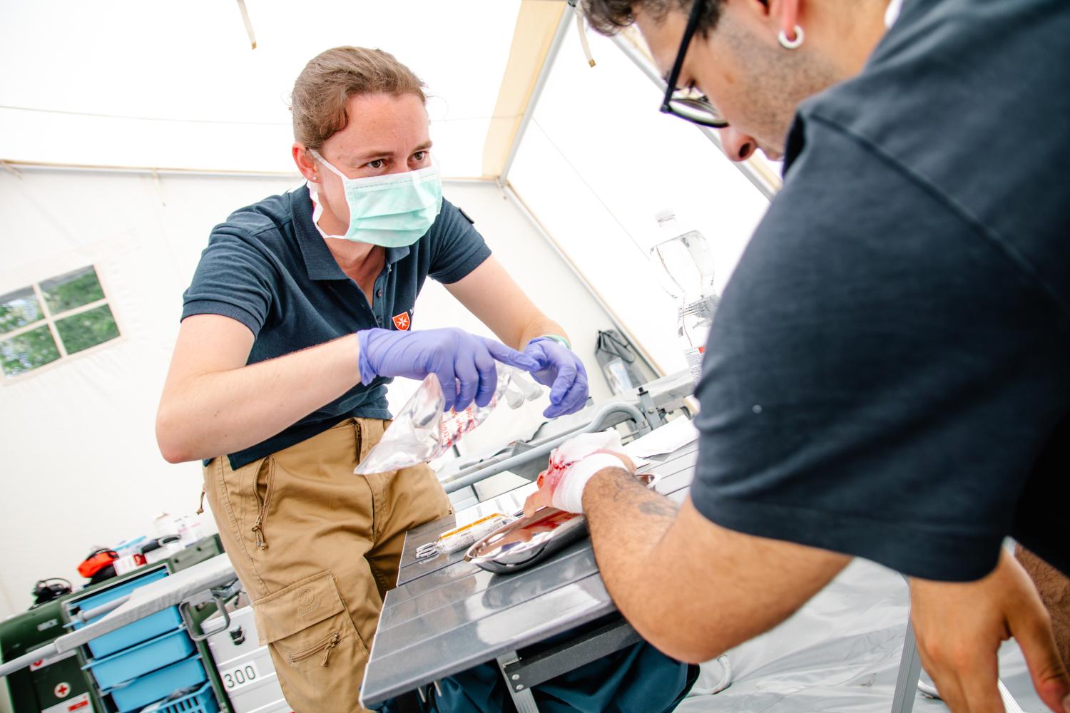 Emergency medical team members are working in a mobile hospital unit.