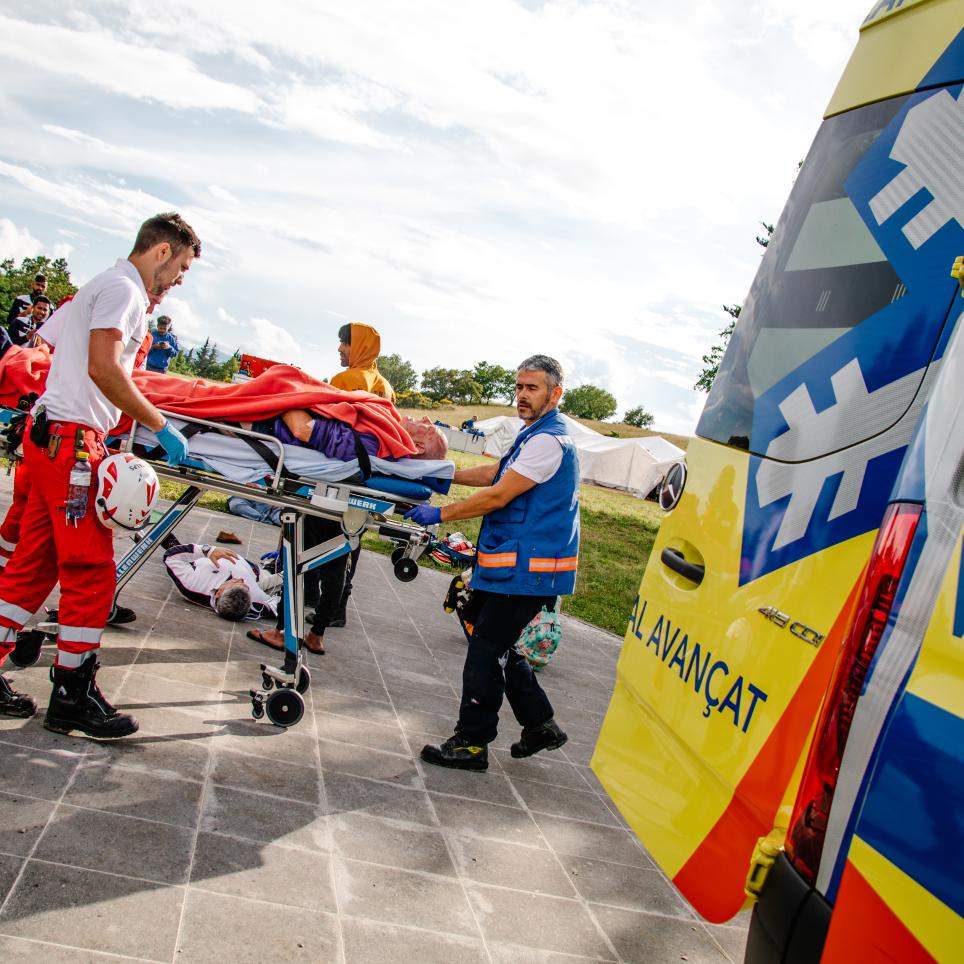 Emergency medical personnel transport an person on a stretcher to an ambulance.