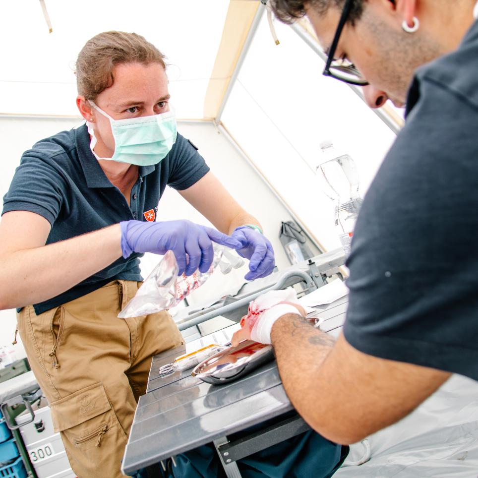 Emergency medical team members are working in a mobile hospital unit.