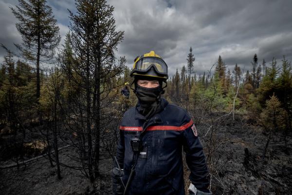 A firefighter from France is masked for protection from smoke and insects in the woodlands as he battles wildfires in the central Mauricie region of Quebec Canada.   