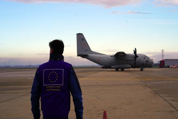 person in EU civil protection jacket in front of plane
