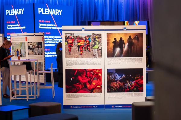 Photo exhibition at a conference setting, with four images displaying disaster situations.