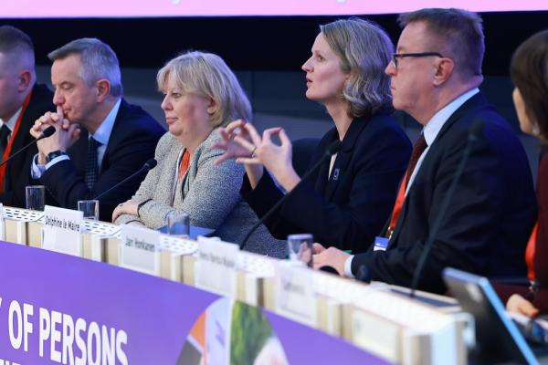 LeMaire during her keynote at the panel. She is seated next to other speakers. She signs her keynote.
