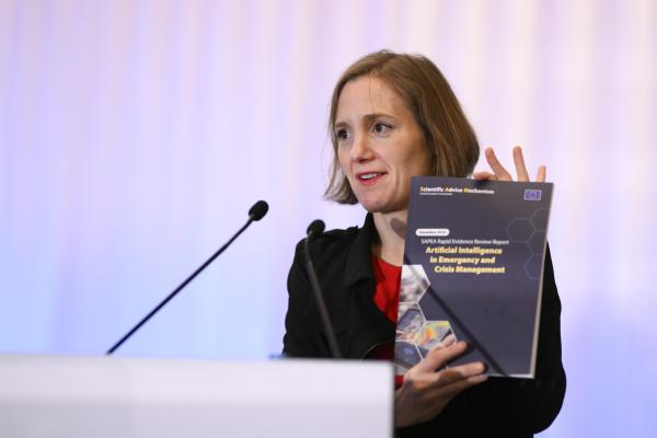 Full Professor Tina Comes during her presentation of the SAM Report, on stage, physically showing the report.