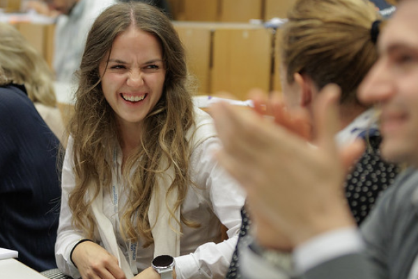 A woman laughing together with other participants of the 2024 Summer School in a lecture hall