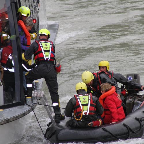 Civil protection personnel training open water rescue in Austria. Staff are wearing protection gear and transferring people from a ship to a dinghy
