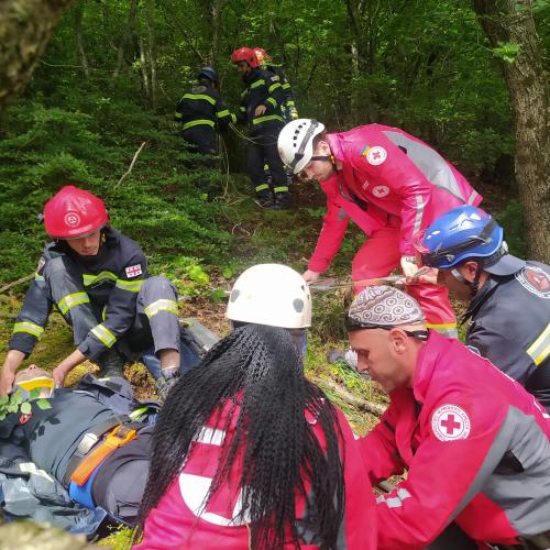 Exercise participants in Red Cross uniforms are working on a rescue of an injured person.