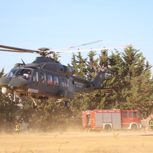 Helicopter taking off a sand field.