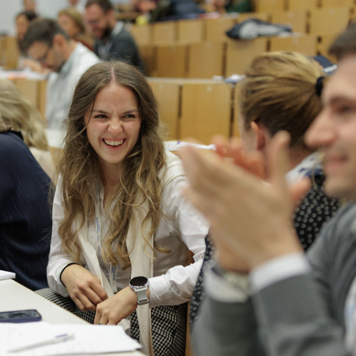 A woman laughing together with other participants of the 2024 Summer School in a lecture hall
