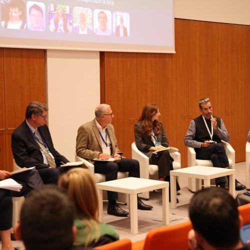 Man speaking during break out session. He is seated next to six other panel members.