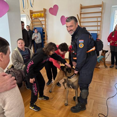 A first responder and his dog showcase their work to a group of people with different types of disabilities.