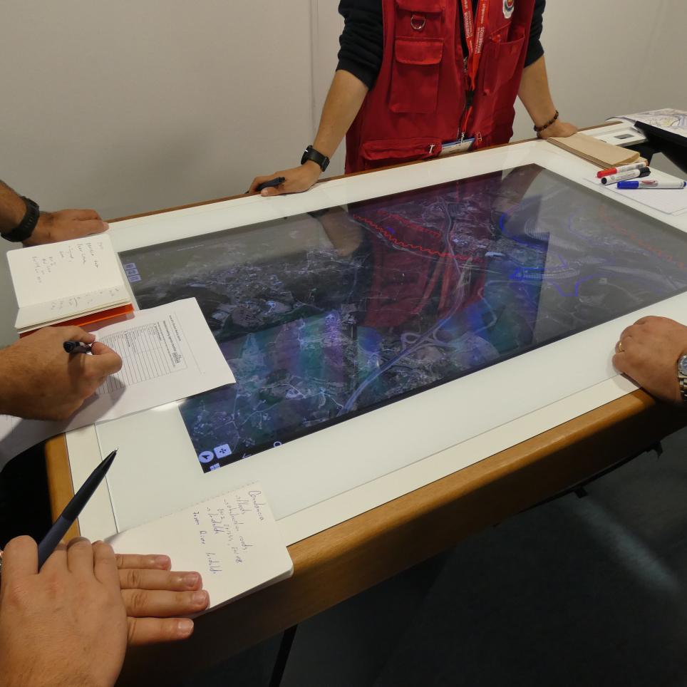 Modules meet with on site commander. Situation is depicted on a digital board.