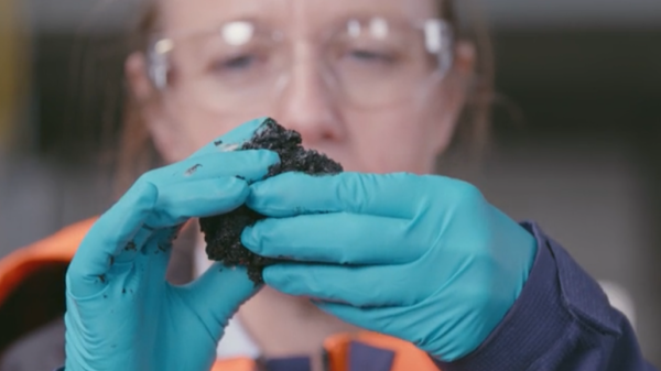 Woman holding a lump of LSFO oil. 