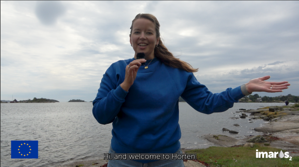 Women talking in a microphone in front of the ocean. 